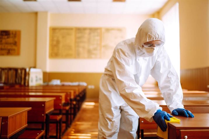 Professional cleaner sanitizing a workspace at Cleanie